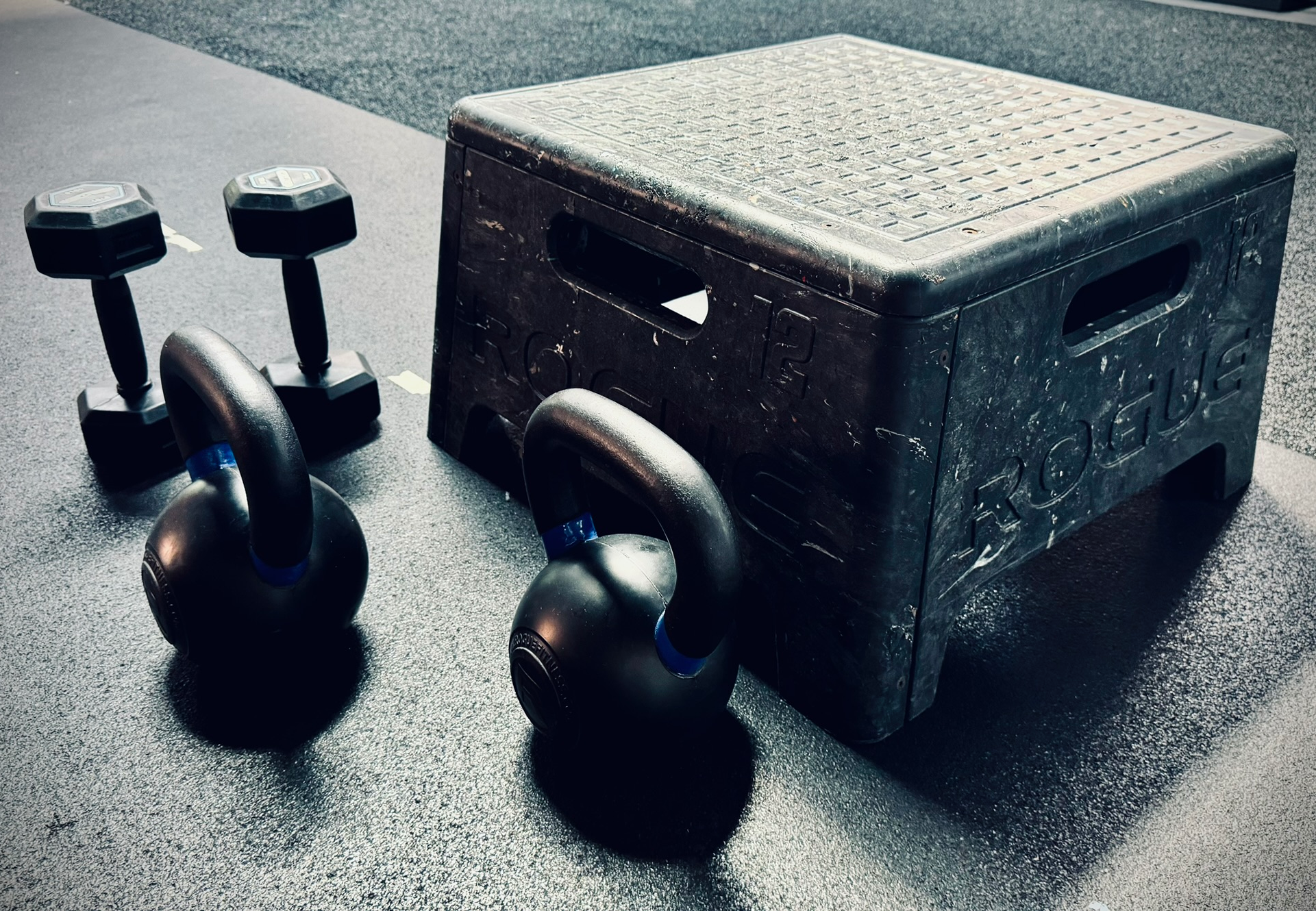 A box and two kettlebells are sitting on the floor.