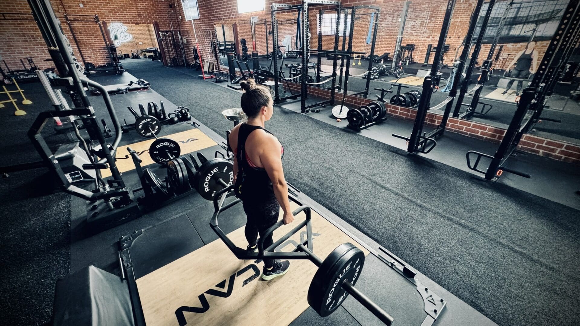 A man is standing in the gym holding a barbell.