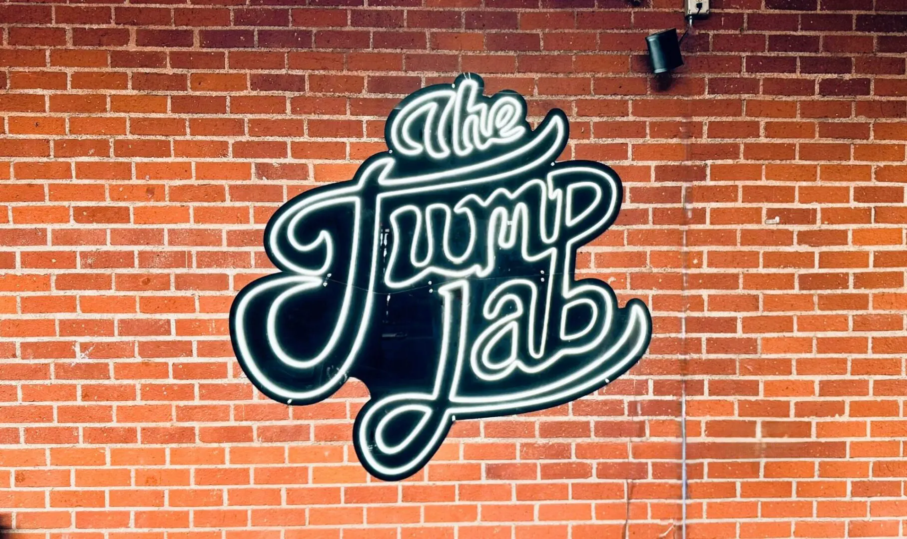 A brick wall with the word jump lab written in neon.