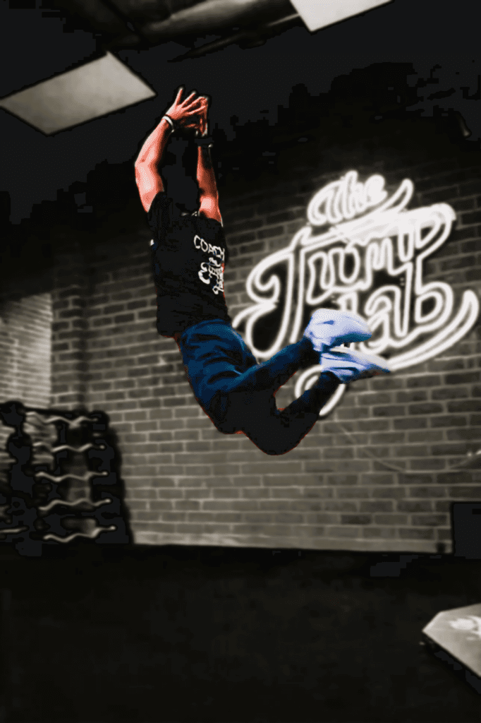 Athlete leaping in gym with neon sign