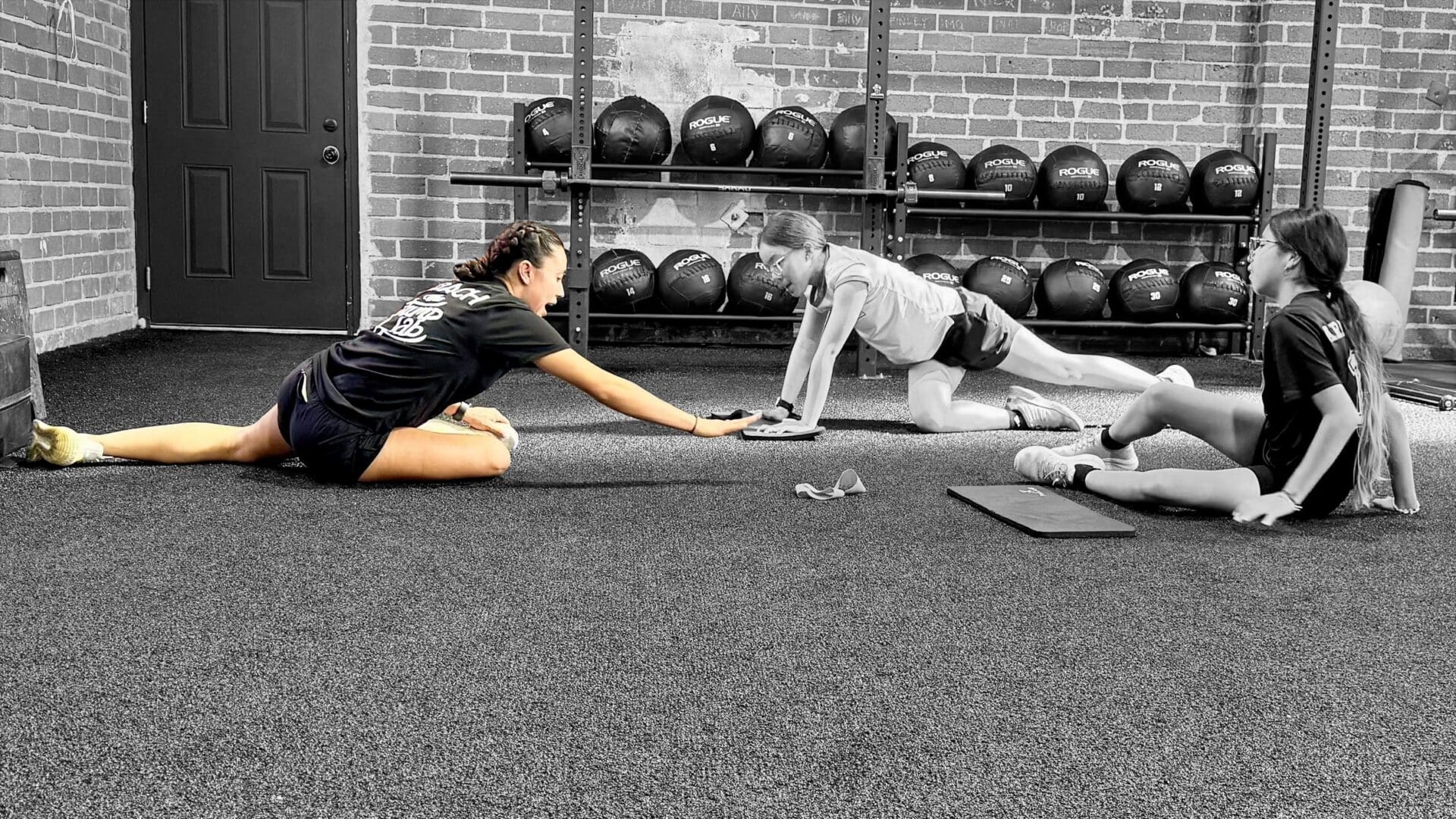 Three women stretching on gym floor